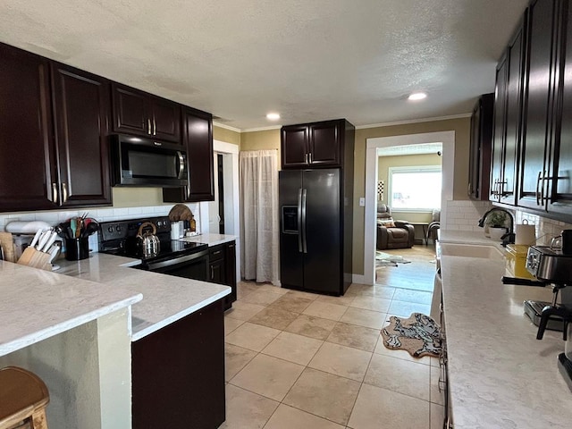 kitchen with a sink, tasteful backsplash, black appliances, and light countertops