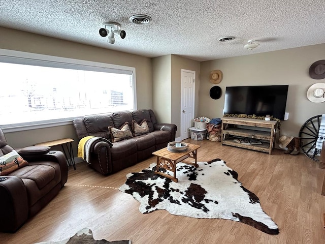 living room with wood finished floors, visible vents, and a textured ceiling