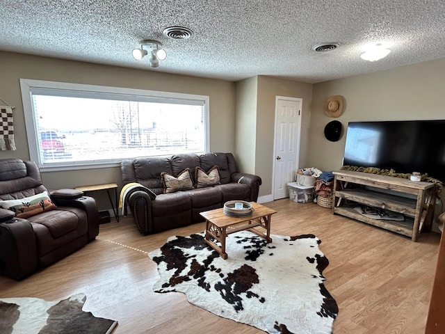 living area featuring visible vents, a textured ceiling, and wood finished floors