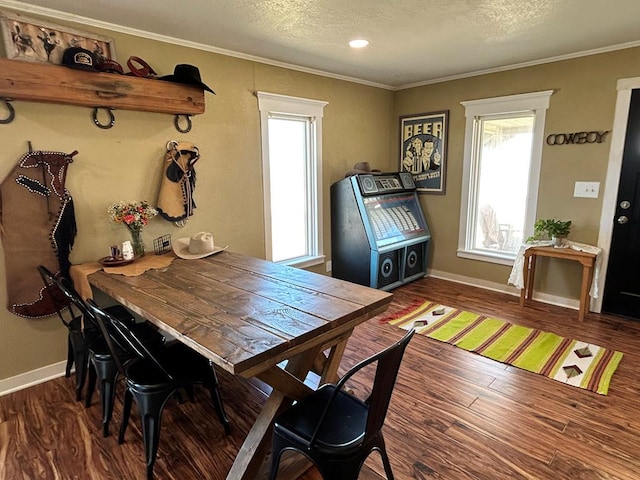 dining room with a textured ceiling, wood finished floors, baseboards, and ornamental molding