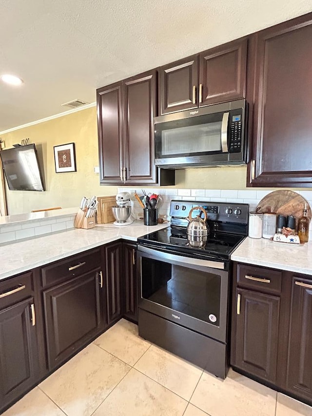 kitchen with dark brown cabinetry, visible vents, tasteful backsplash, and stainless steel appliances