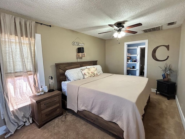 bedroom featuring a textured ceiling, a ceiling fan, visible vents, and light carpet