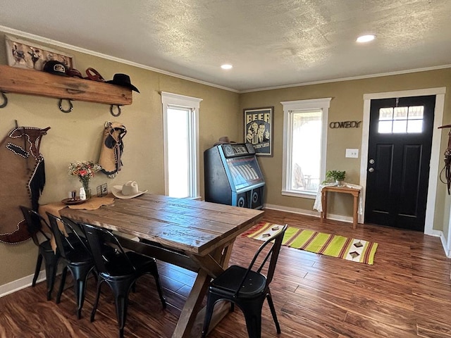 dining space featuring ornamental molding, a textured ceiling, baseboards, and wood finished floors