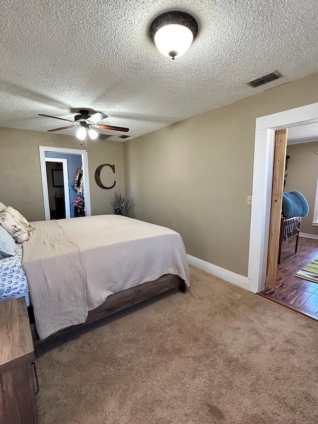 carpeted bedroom featuring baseboards, visible vents, a textured ceiling, and a ceiling fan