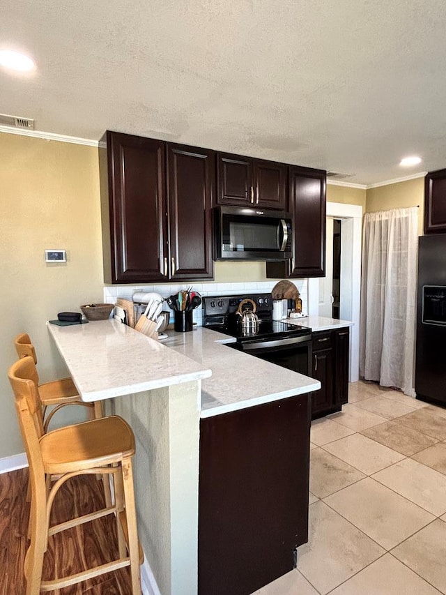 kitchen with visible vents, black appliances, a peninsula, and light countertops