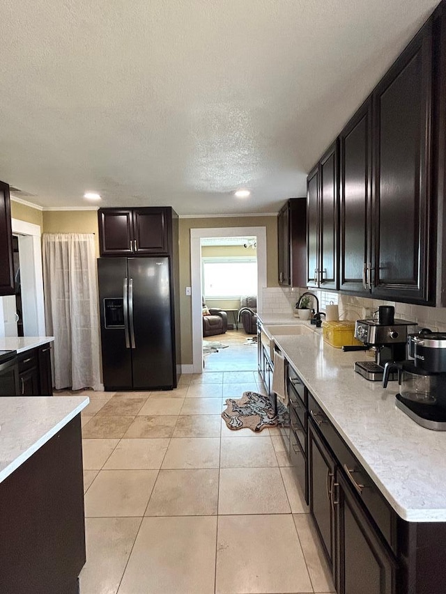 kitchen with light tile patterned floors, a textured ceiling, light countertops, and black refrigerator with ice dispenser