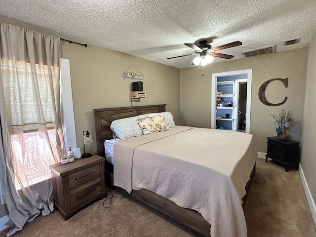 bedroom featuring a textured ceiling, light colored carpet, visible vents, and ceiling fan