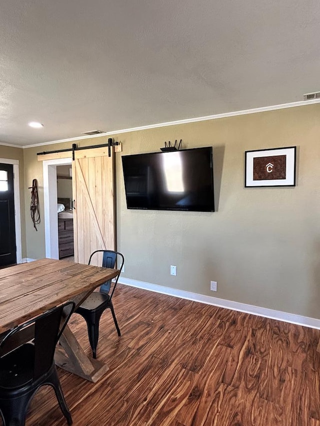 dining area featuring a barn door, visible vents, wood finished floors, and crown molding