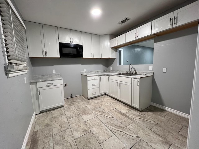 614 W Nobles Ave, Midland, TX 79701 - kitchen with black microwave, a sink, baseboards, and light countertops