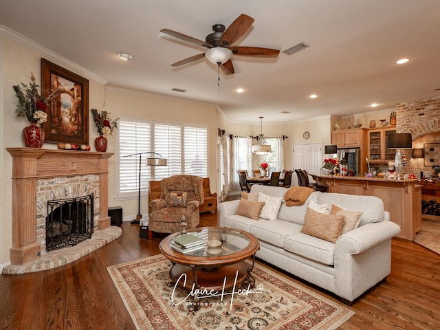 living room with ceiling fan, a fireplace, crown molding, and dark wood-type flooring