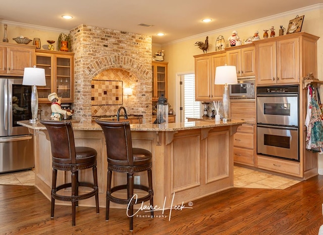 kitchen featuring a kitchen island with sink, light wood finished floors, tasteful backsplash, and appliances with stainless steel finishes