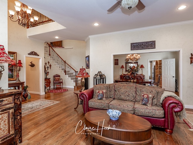 living room with ceiling fan with notable chandelier, hardwood / wood-style flooring, and crown molding