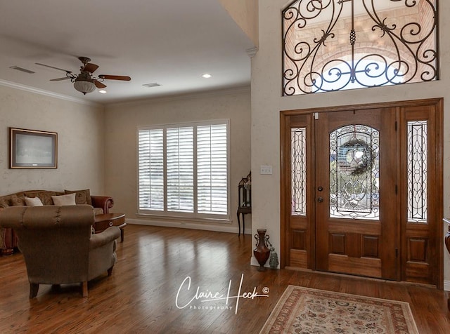 foyer entrance featuring a ceiling fan, crown molding, wood finished floors, and visible vents