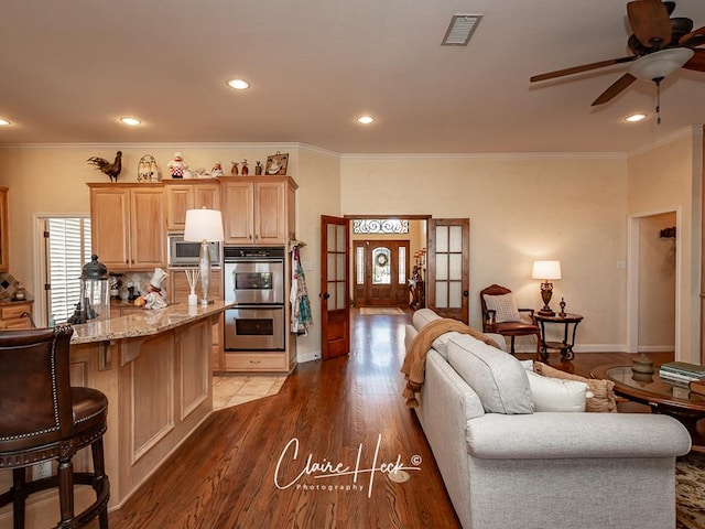 kitchen with visible vents, crown molding, a breakfast bar, appliances with stainless steel finishes, and wood finished floors