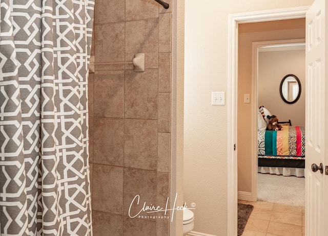 bathroom featuring baseboards, toilet, tiled shower, tile patterned floors, and ensuite bath