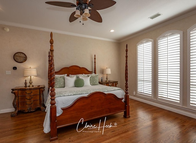 bedroom featuring a ceiling fan, wood finished floors, visible vents, and ornamental molding