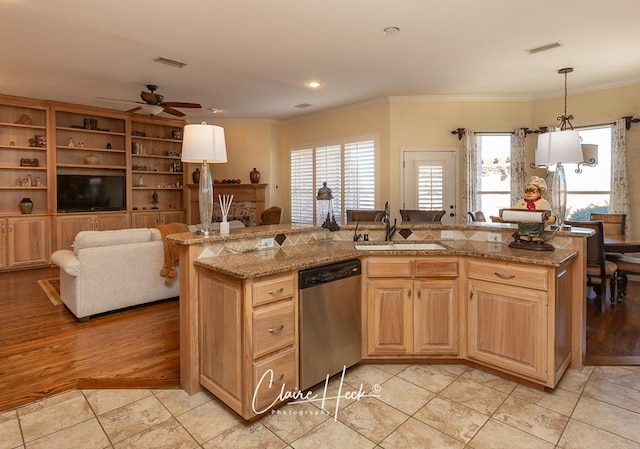 kitchen with light tile patterned flooring, a kitchen island with sink, ornamental molding, a sink, and stainless steel dishwasher