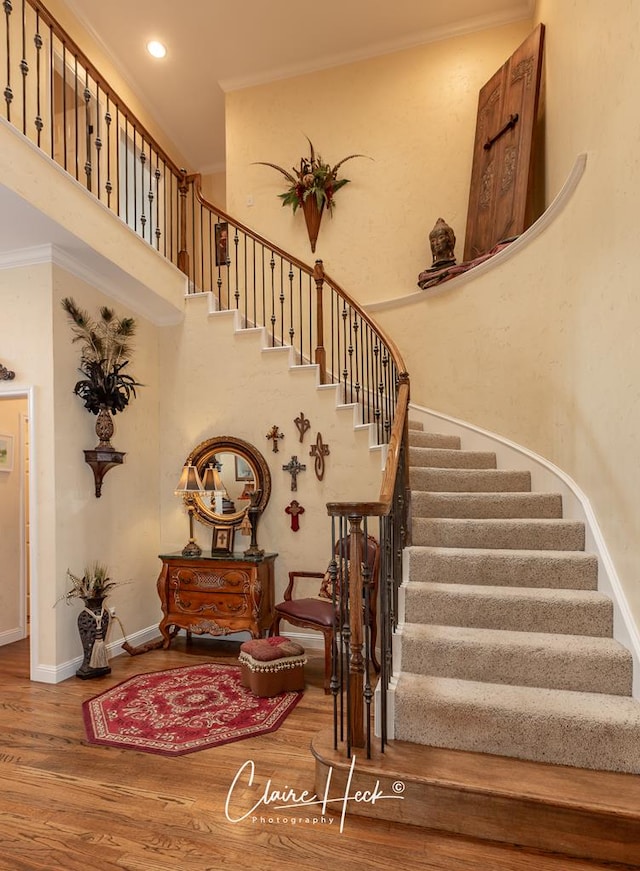 stairway with hardwood / wood-style flooring and ornamental molding