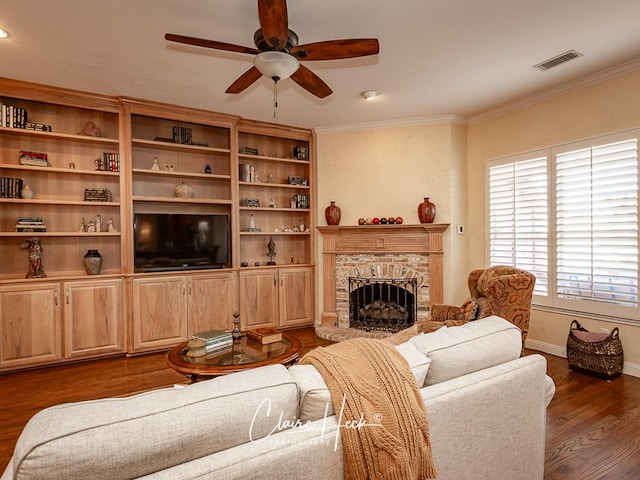 living area with baseboards, visible vents, dark wood finished floors, a fireplace, and ornamental molding