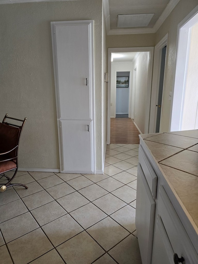 corridor with crown molding, baseboards, a textured wall, and light tile patterned flooring