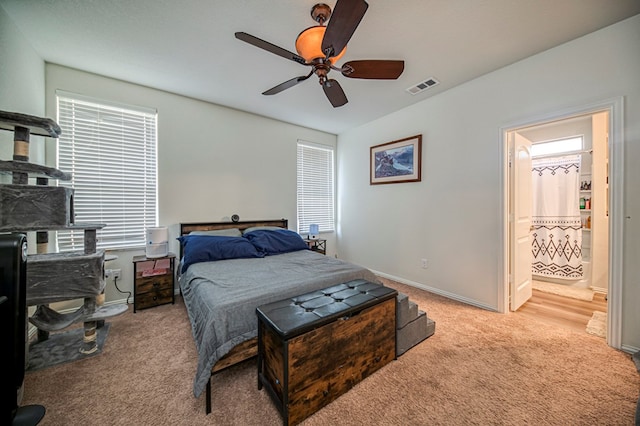 bedroom with ceiling fan, light carpet, and ensuite bath