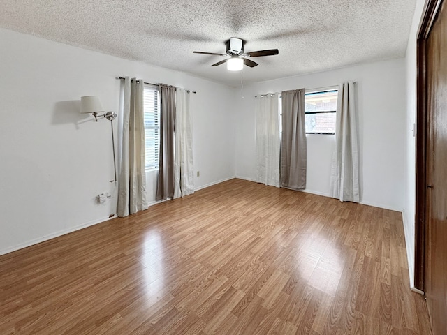 empty room featuring a textured ceiling, light hardwood / wood-style floors, and ceiling fan