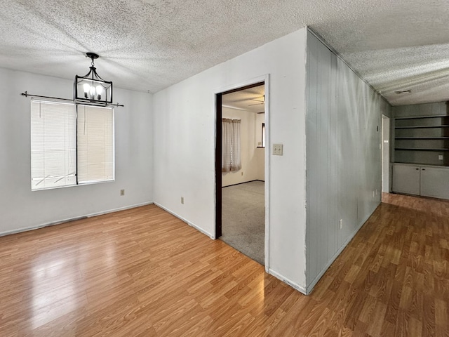 unfurnished dining area with hardwood / wood-style floors, a textured ceiling, and a notable chandelier