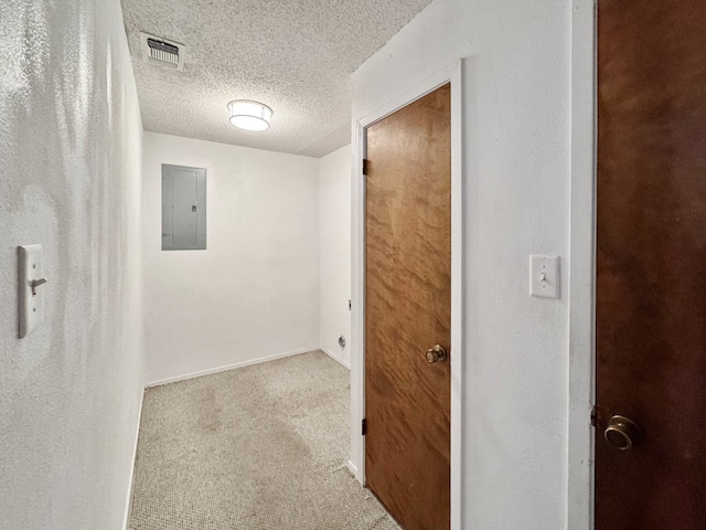 hallway featuring light colored carpet, electric panel, and a textured ceiling