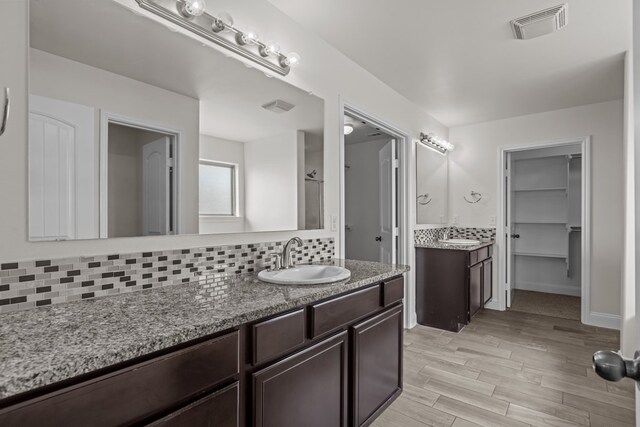 1306 Randolph Ln, Midland, TX 79705 - full bathroom featuring decorative backsplash, two vanities, and wood finished floors