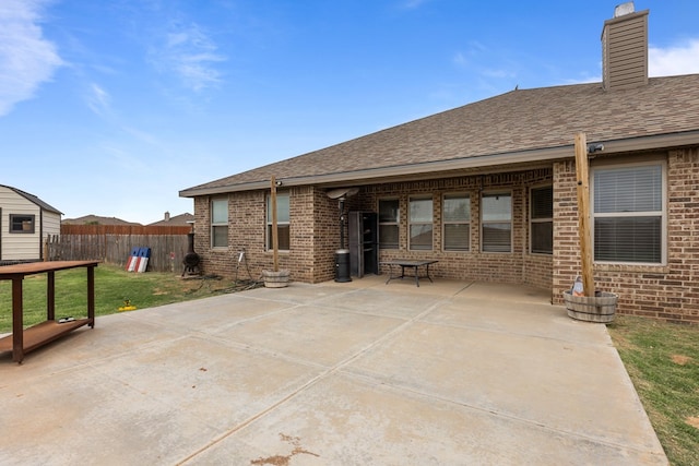 1306 Randolph Ln, Midland, TX 79705 - back of property featuring brick siding, a patio, a chimney, and a shingled roof
