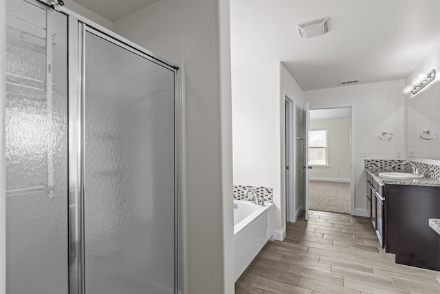 1306 Randolph Ln, Midland, TX 79705 - full bathroom featuring vanity, a stall shower, a garden tub, and wood finished floors