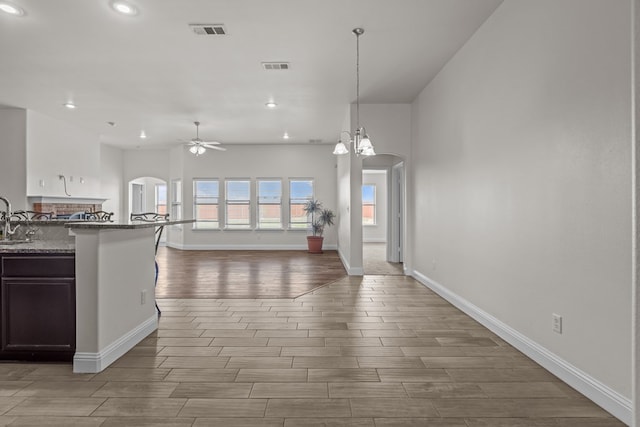 1306 Randolph Ln, Midland, TX 79705 - kitchen featuring arched walkways, wood finished floors, ceiling fan, recessed lighting, and baseboards