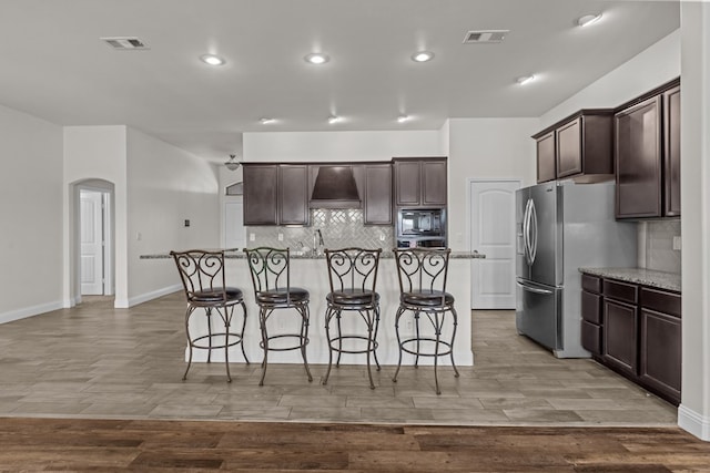 1306 Randolph Ln, Midland, TX 79705 - kitchen with black microwave, arched walkways, dark brown cabinetry, a kitchen breakfast bar, and recessed lighting