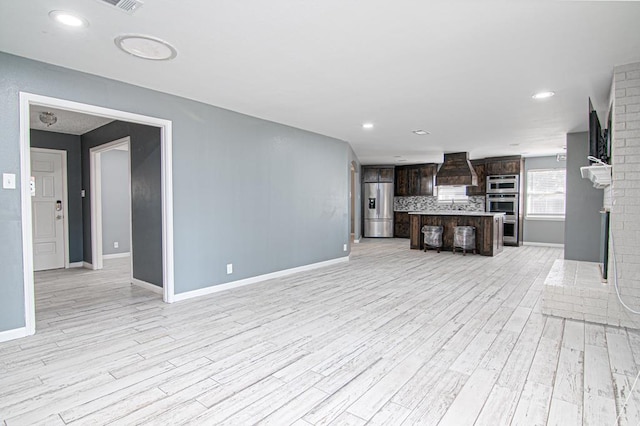 unfurnished living room featuring light hardwood / wood-style floors and a brick fireplace