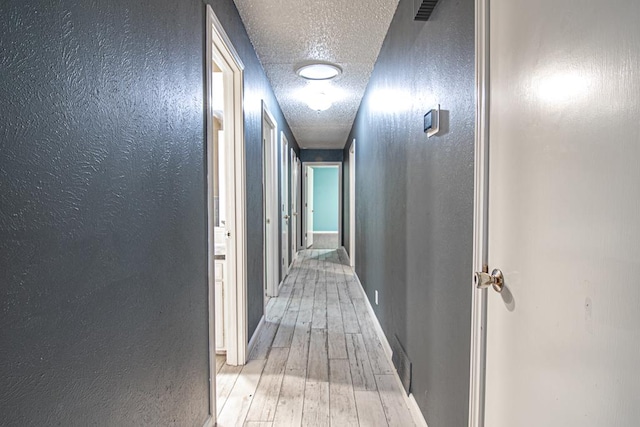 hall featuring a textured ceiling and light wood-type flooring