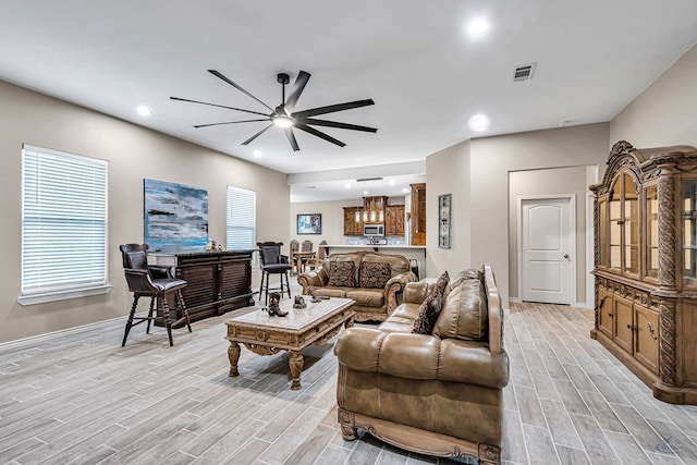 living room featuring ceiling fan, a healthy amount of sunlight, and bar