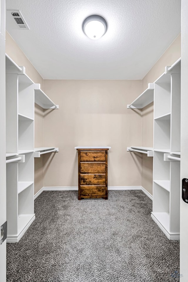 walk in closet featuring dark carpet