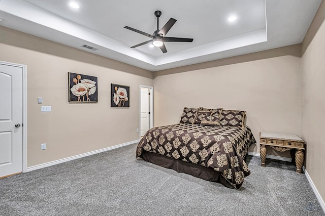 carpeted bedroom with a raised ceiling and ceiling fan