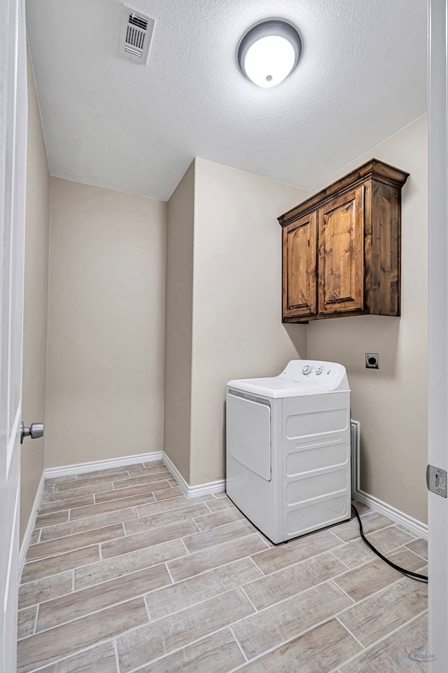 washroom with cabinets, washer / dryer, and a textured ceiling