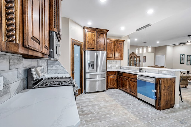 kitchen with pendant lighting, kitchen peninsula, backsplash, and appliances with stainless steel finishes