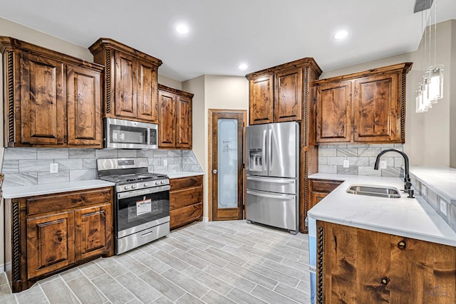 kitchen with backsplash, sink, stainless steel appliances, and decorative light fixtures