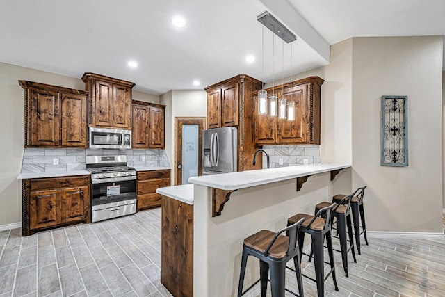 kitchen with a breakfast bar area, decorative backsplash, stainless steel appliances, and decorative light fixtures