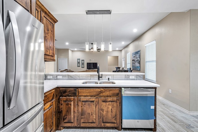 kitchen featuring kitchen peninsula, sink, hanging light fixtures, and appliances with stainless steel finishes