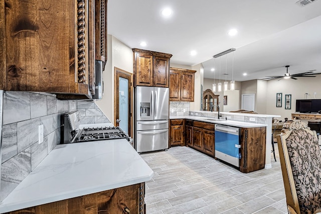 kitchen featuring kitchen peninsula, decorative backsplash, decorative light fixtures, and appliances with stainless steel finishes