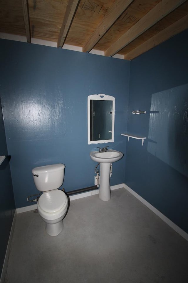 bathroom with concrete flooring, sink, wooden ceiling, beamed ceiling, and toilet