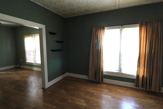 spare room with plenty of natural light and dark wood-type flooring