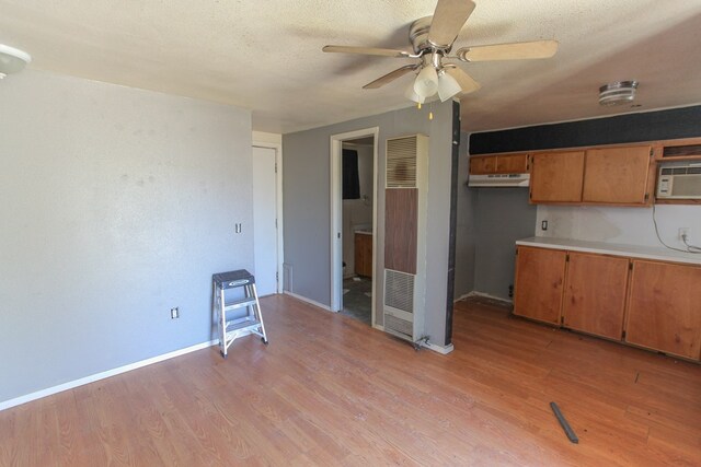 kitchen featuring a textured ceiling, light hardwood / wood-style flooring, ceiling fan, and a wall unit AC