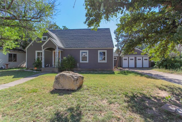 view of front facade featuring a garage, a front lawn, and an outdoor structure