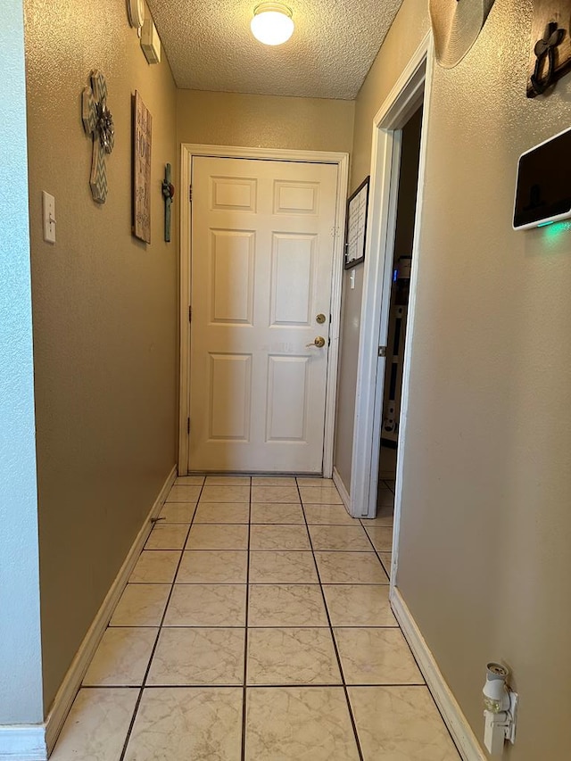 corridor featuring a textured ceiling and light tile patterned flooring