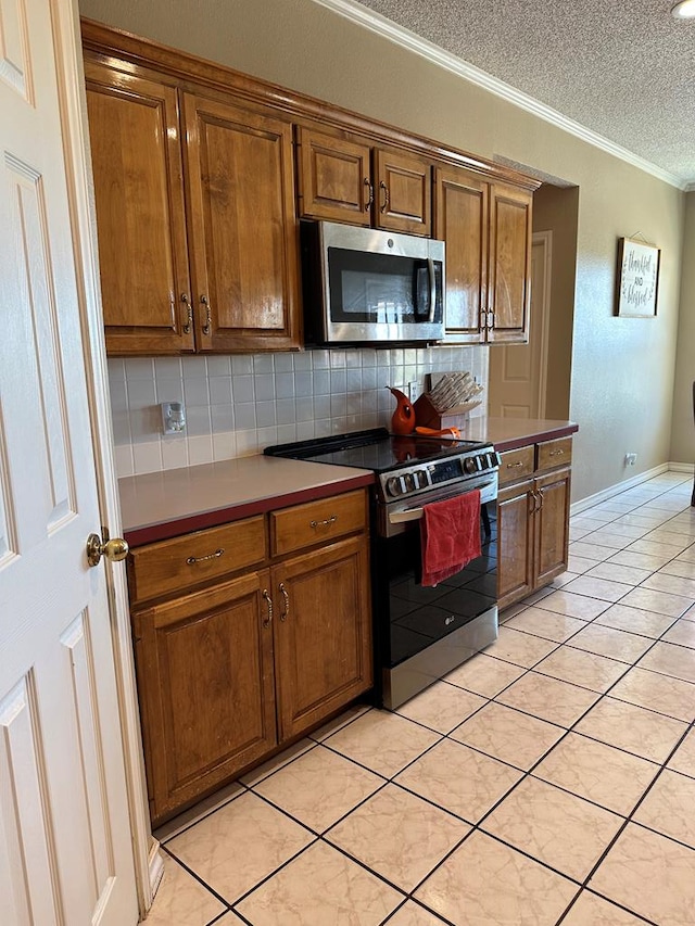 kitchen with stainless steel appliances, tasteful backsplash, crown molding, a textured ceiling, and light tile patterned flooring